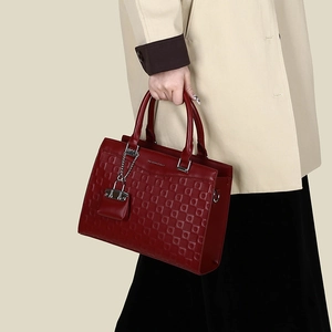 Detail of burgundy embossed leather tote featuring silver chain and textured square pattern