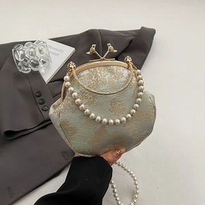 Retro jacquard shell bag with pearl handle and golden bird clasp on a grey blazer