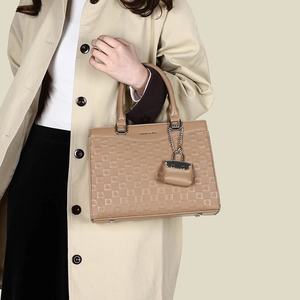 Detail of khaki tote bag featuring embossed grid texture and Balado logo with mini charm