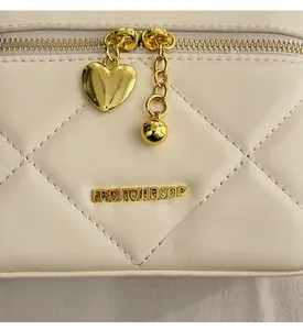 Macro detail of cream quilted bag with golden heart charm and Fashion Bags logo