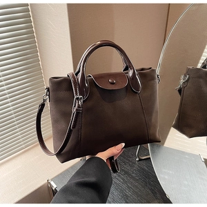 Detail of dark brown tote bag with contrast matte suede and glossy patent leather textures
