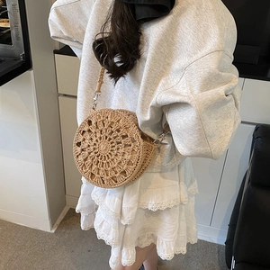 Handcrafted circular straw crossbody bag with bohemian tassels and woven shoulder strap