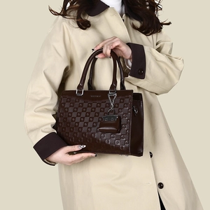 Detailed close-up of geometric embossed dark brown tote bag with silver hardware accents