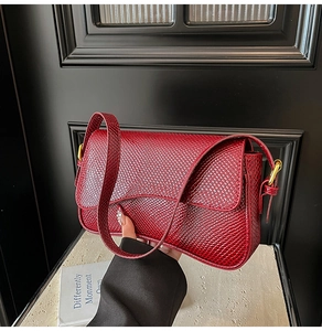 Détail de la texture serpent bordeaux sur le sac à rabat avec boucle dorée