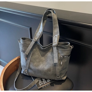 Detail der grauen Vintage-Tasche mit matter Textur, Nieten und seitlichen Reißverschlüssen