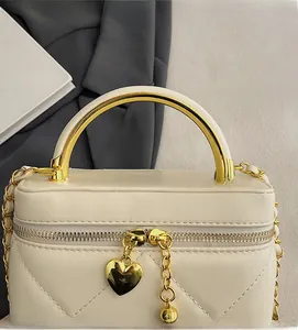 Close-up of quilted cream handbag with gold arch handle and heart zipper charms