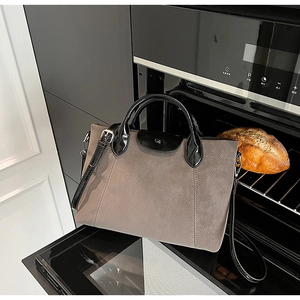 Detail of contrast stitch tote bag with suede texture and leather handle in a creative setting