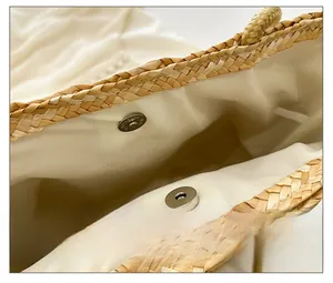 Detail view of the secure magnetic closure and woven texture on a beige straw bucket bag