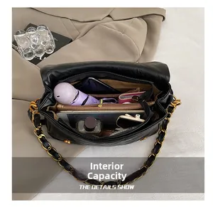 Detailed internal capacity of black quilted crossbody bag with golden chain strap