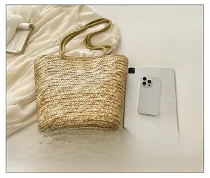 Top view of a spacious hand-woven straw tote bag with books and electronics for travel