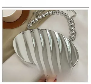 Detail of silver shell-shaped evening bag with wave texture and bead chain handle