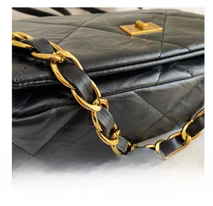 Detail of black quilted leather handbag with gold chain strap and metal turn-lock