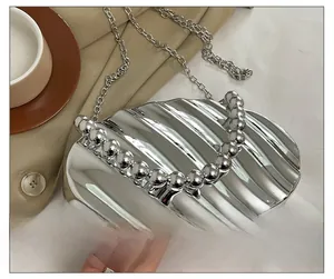 Detail shot of silver acrylic seashell handbag with chain strap and beaded handle