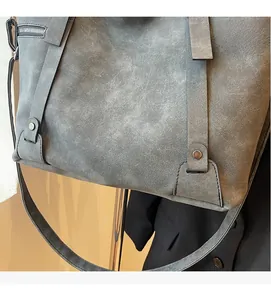 Makroaufnahme der graublauen Wildleder-Einkaufstasche mit Metallzippern und Nietendetails
