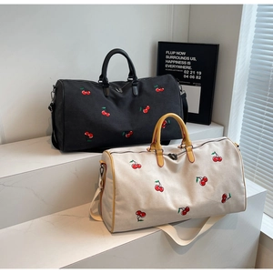 Detail of travel tote bags with cherry embroidery on marble stand in natural light