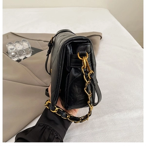 Detail of black quilted leather crossbody bag featuring vintage gold chain and fine stitching
