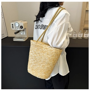 Detail of hand-woven straw tote bag with fine texture and slim shoulder straps