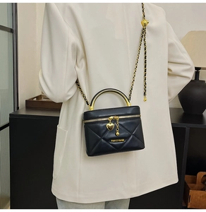 Close-up of quilted mini crossbody bag with golden chain strap and heart charm detail