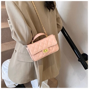 Pink quilted leather chain bag with golden lock shown on a model in urban setting