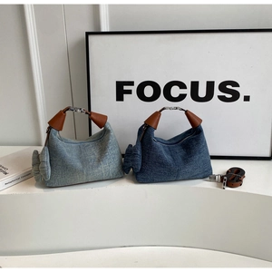 Detail of denim texture handbags with brown leather handles and side ribbon accents