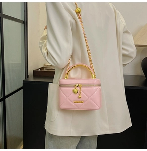 Detailed close-up of pink quilted mini bag with golden metal handle and heart charm