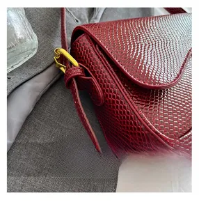 Détail de la texture serpent rouge foncé et des finitions métalliques dorées