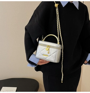 Detail of silver quilted handbag with gold circular handle and heart pendant charm