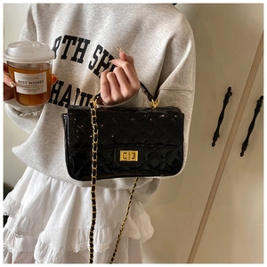 Close-up of black quilted leather bag with gold chain strap and metallic clasp closure