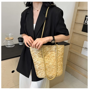 Detail of hand-woven straw tote bag with long straps shown in a stylish indoor setting