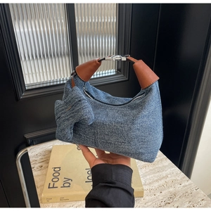 Detail of denim shoulder bag with leather handle and side bow knot decoration