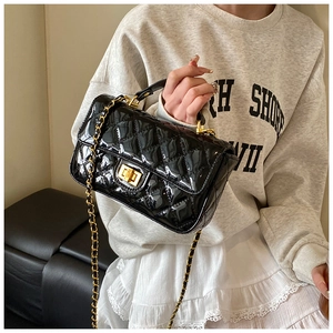 Detail view of black patent leather shoulder bag with gold chain and quilted texture