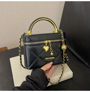 Detail of black quilted crossbody bag with gold metal handle and chain strap