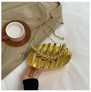 Detailed view of golden acrylic evening bag with wave texture and beaded handle