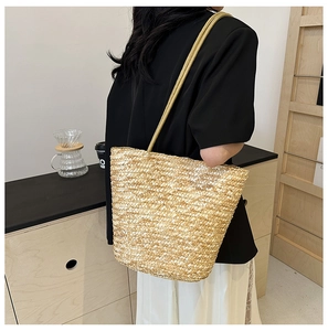 Close-up of woven straw bucket bag with thick rope shoulder strap for summer beach style