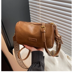 Sac bandoulière cylindrique en cuir marron avec étiquette mode et deux sangles