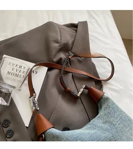 Detail of adjustable brown leather shoulder strap with silver buckle on denim handbag
