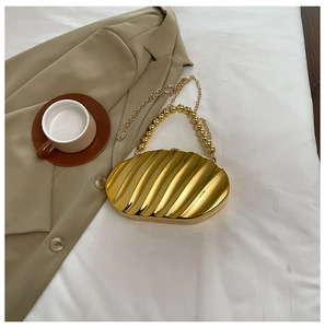 Close-up of golden shell-shaped evening clutch with beaded handle and chain strap
