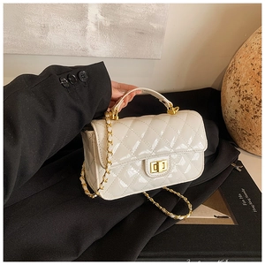 Close-up of white glossy patent leather quilted bag with gold chain and turn-lock closure