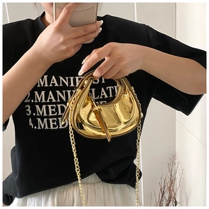 Detail of a mini golden metallic crescent handbag with fine chain strap and glossy finish