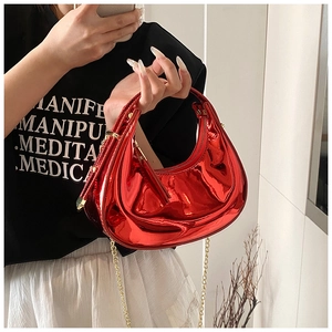 Detailed macro view of red glossy patent leather hobo bag with elegant gold chain strap