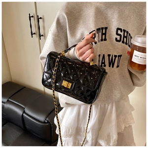 Detail of black quilted patent leather crossbody bag with gold twist lock and chain strap