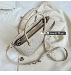 Dettaglio macro della cerniera in metallo su una borsa tote intrecciata bianco crema