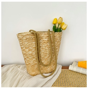Close-up of handwoven straw bucket bag with dark rope handles and yellow tulip accents
