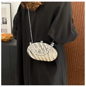 Detail of silver metallic evening bag featuring vertical wavy pleats and bead handle