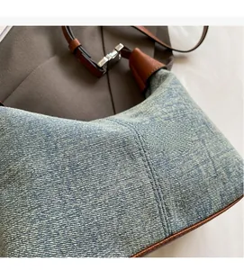 Detail of washed denim texture with brown leather trim and silver buckle on shoulder bag