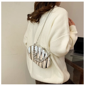 Detail of silver metallic wavy evening bag with round bead handle and crossbody chain