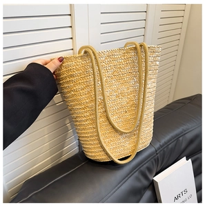 Detail of hand-woven straw bucket bag with thick rope handles for summer vacation