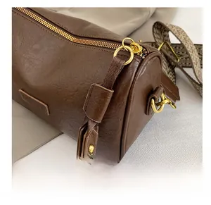 Détail du sac cylindre marron avec fermeture éclair dorée et bandoulière ethnique