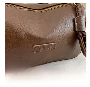 Détail du sac marron avec texture cuir, fermeture dorée et étiquette de mode