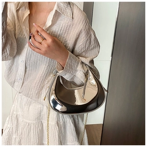 Close-up of a silver mirror crescent hobo bag featuring a fine gold chain shoulder strap